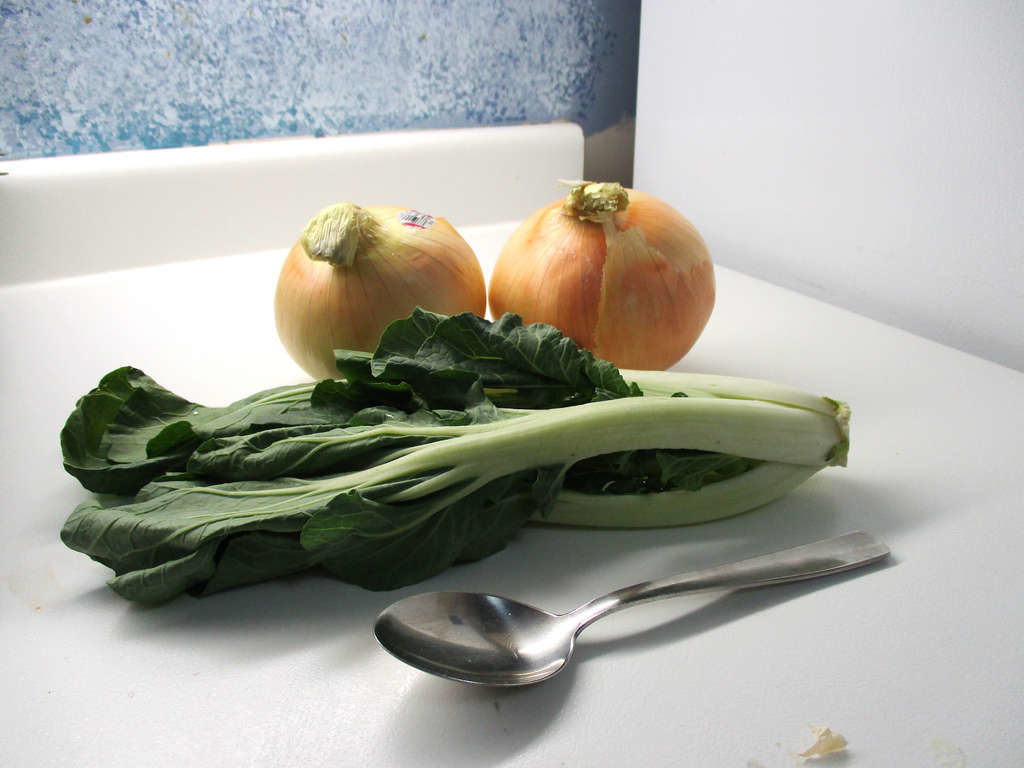 Low angle view of big onions with bok choi and spoon for scale